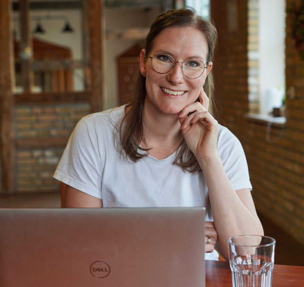 Mirjam sitzt lächelnd am Laptop